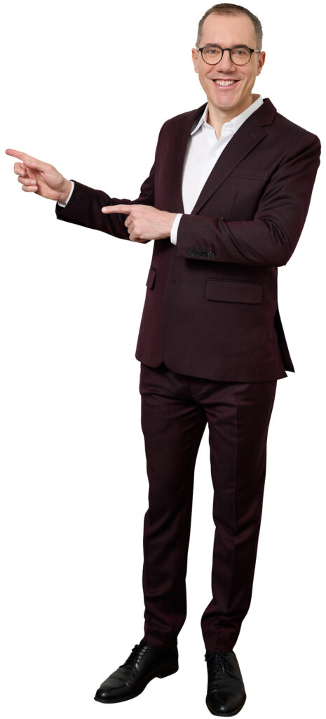 Smiling man in a burgundy suit points to the left and right against a white background.