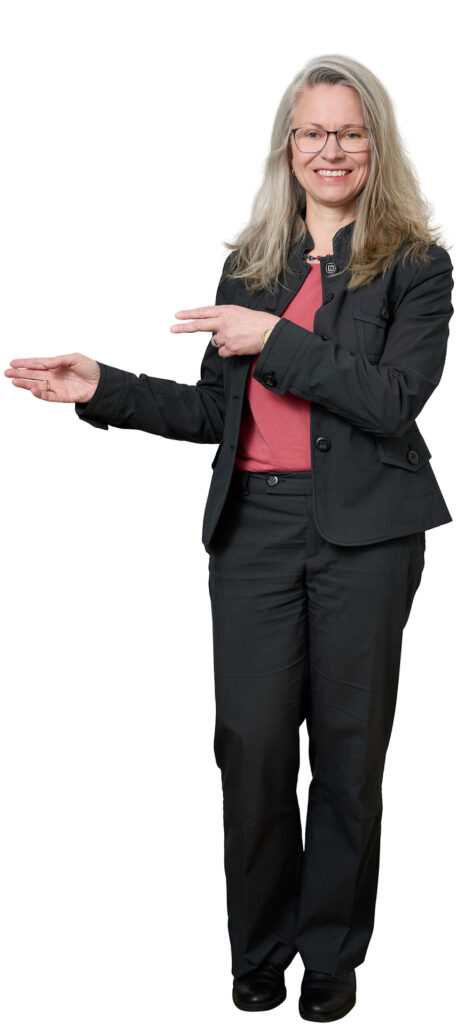 Smiling woman with gray hair and glasses in a black suit and red top, gesturing with her hands as if presenting.
